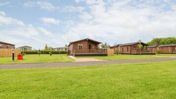 A row of wooden cabins with a grassy lawn in front.