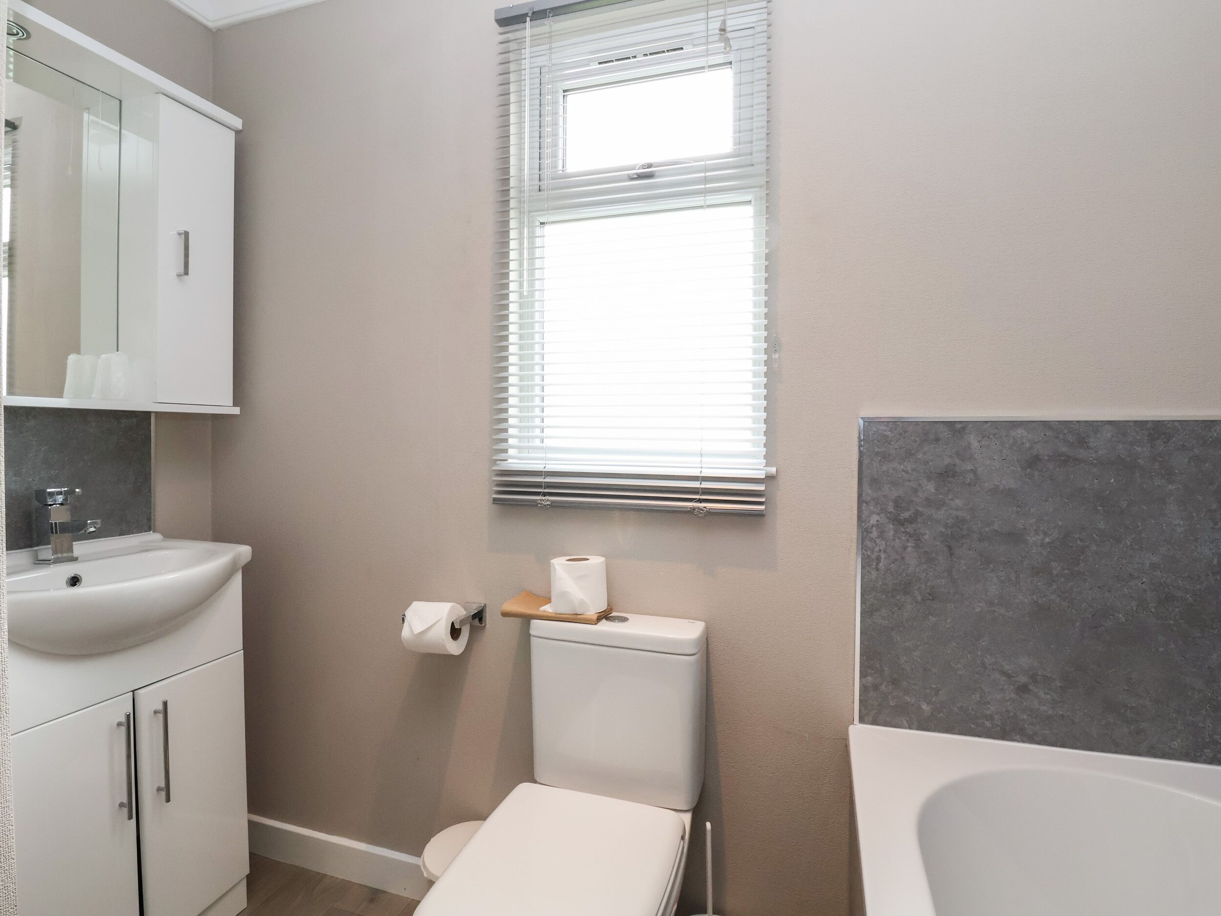 A bathroom with a toilet, sink, and window.