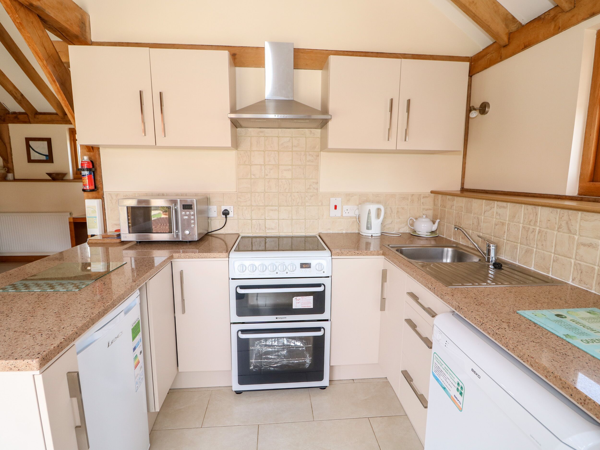 A compact kitchen with a microwave, toaster, kettle, and a built-in oven.
