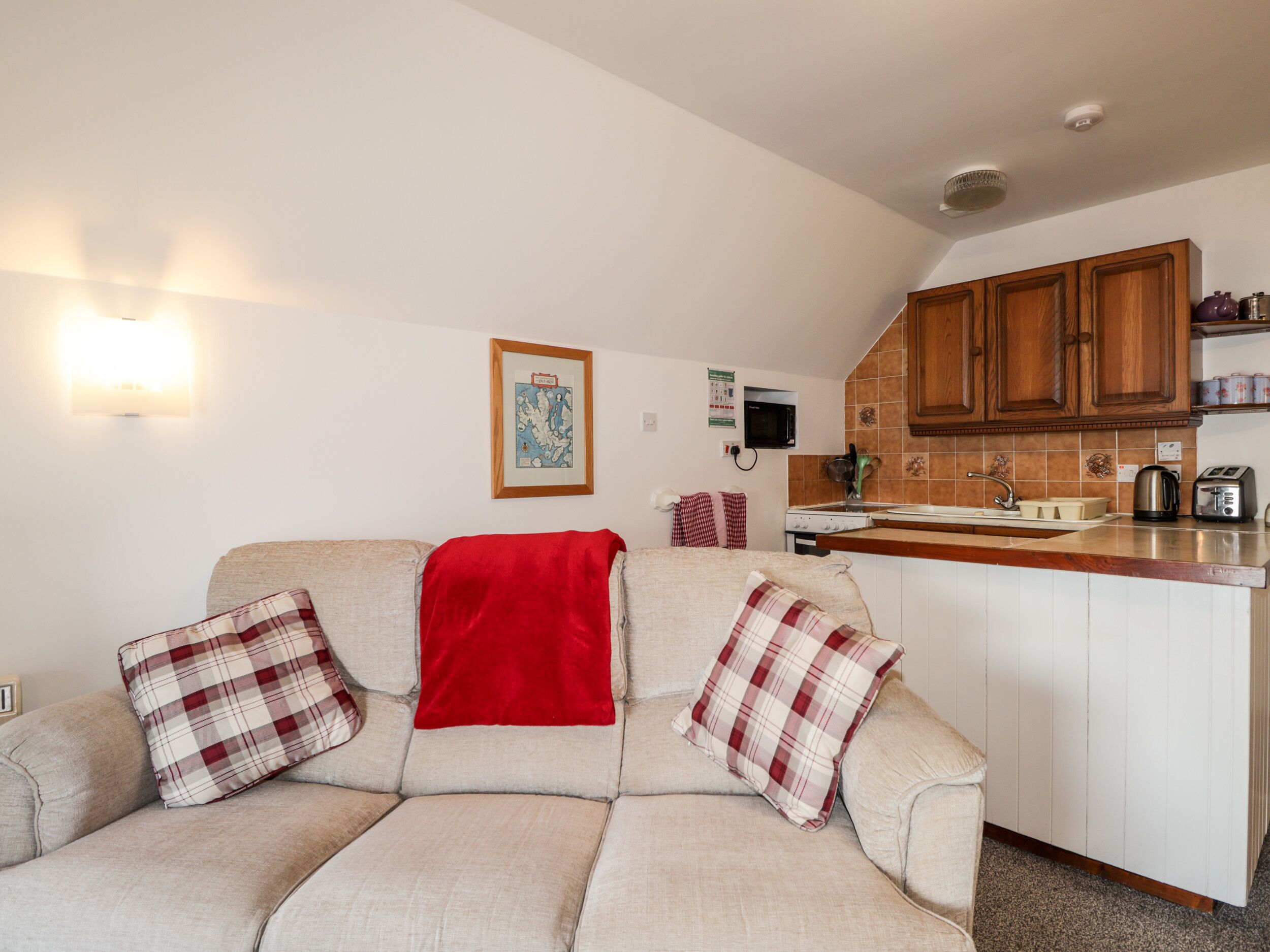 A cozy living room with a sofa and a kitchen area in the background.