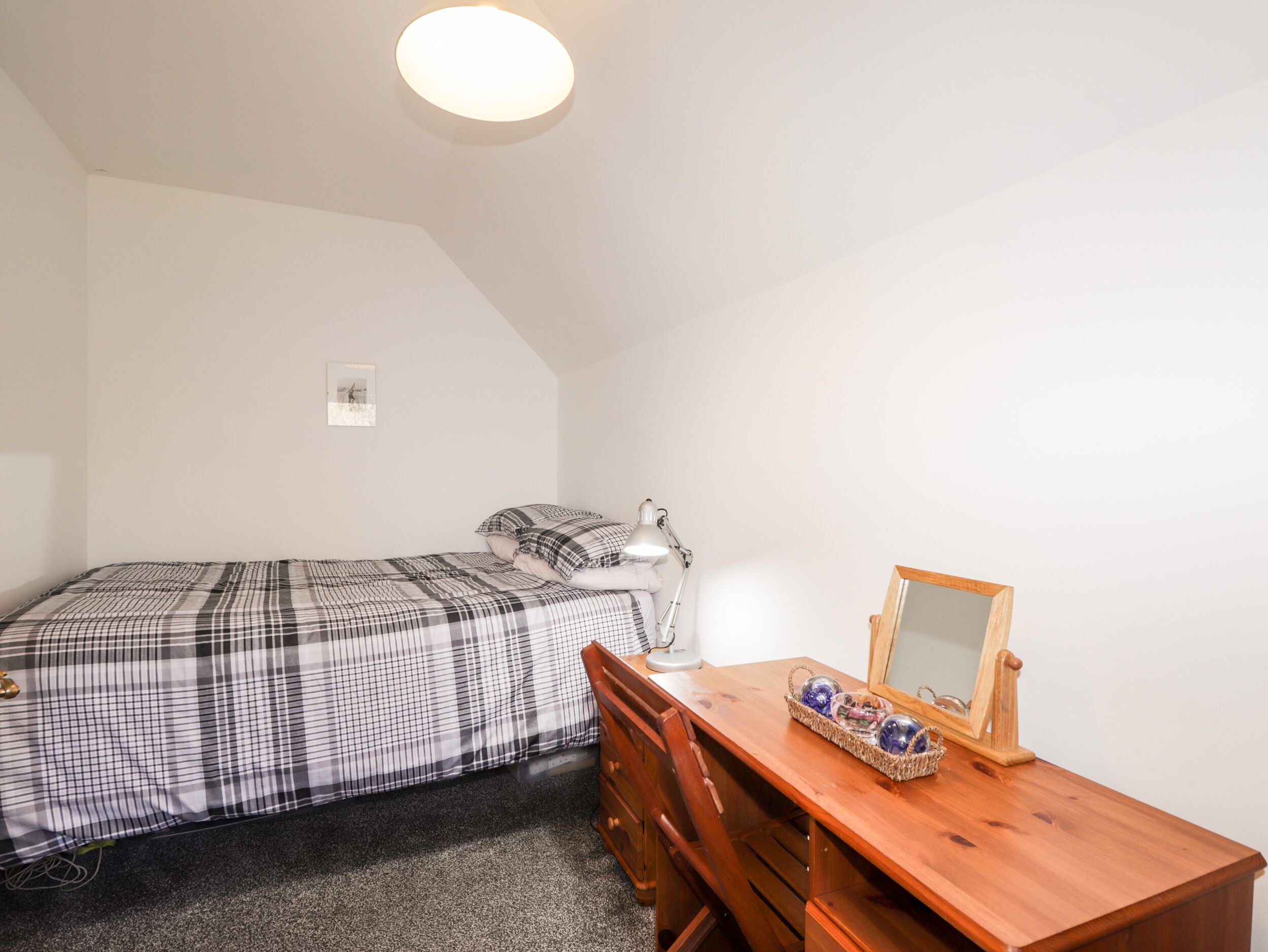Un dormitorio pequeño y ordenado con cama, escritorio y silla.