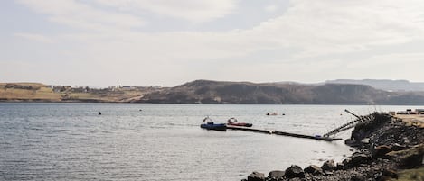 A rocky shoreline with a pier extending into calm water.