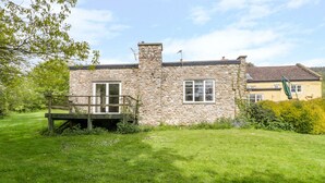 A stone house with a wooden deck and a grassy yard. - Old Ford Farm Annexe (Axminster)