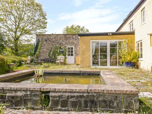 Relax in a serene outdoor space with a stone-built structure, modern building, and tranquil water feature.