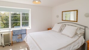 A bedroom with a bed, a window, a radiator, and a mirror. - Old Ford Farm Annexe (Axminster)