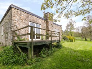 Surrounded by lush greenery, this cottage offers a peaceful outdoor space with a wooden deck.