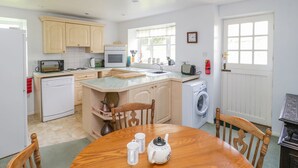 A compact kitchen with a central island, a microwave, a toaster, and a washing machine. - Old Ford Farm Annexe (Axminster)