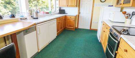 A kitchen with wooden cabinets, a dishwasher, a stove, and a window providing natural light.