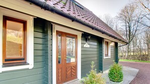 Ein Haus mit dunkelgrüner Fassade, einer braunen Haustür und einem Schild mit der Aufschrift „Lime Tree“. Vor der Veranda stehen zwei Pflanzgefäße.