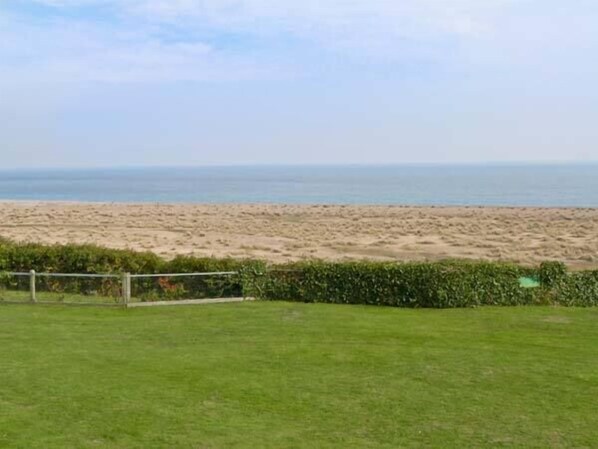 A grassy area with a view of a sandy beach and the ocean in the background. - Seascope (Lowestoft)