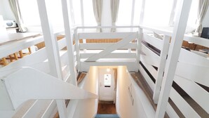 A staircase with white railings and a wooden floor leading to a door with a small window. - Top Flat (Tighnabruaich)