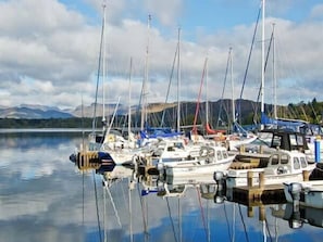 Boats docked in a serene marina, surrounded by majestic mountains.