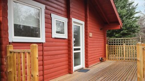 Una casa in legno rossa con veranda in legno e cancello in legno.