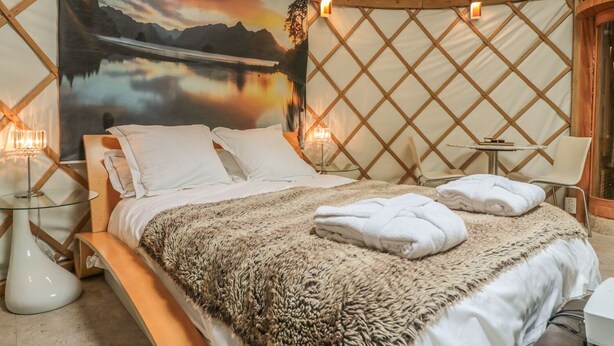 A cozy tented room with a bed, a table, and a chair. - Island Yurt (Tewkesbury)