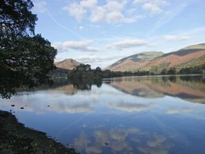 Un lago tranquilo con reflejos claros de las colinas y árboles circundantes.