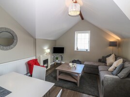 Una sala de estar acogedora con chimenea, televisor, mesa de comedor y un sofá confortable.