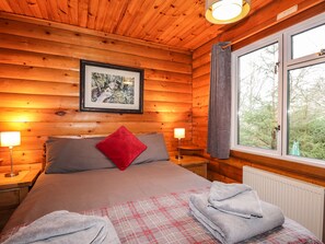 Relax in a serene bedroom with a large bed, framed artwork, and a window with curtains.