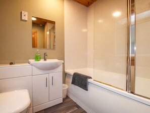 Features a clean bathroom with a sink, mirror, toilet, and shower area.