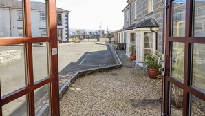 A narrow street with a gravel path, stone buildings, and a gated entrance. - Taliesin (Porthmadog)