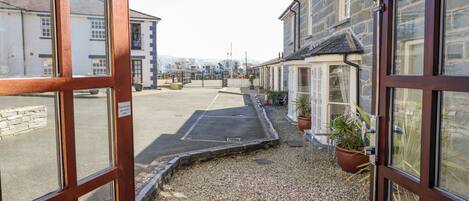 A narrow street with a gravel path, stone buildings, and a gated entrance.