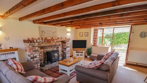 A cozy living room with a fireplace, sofas, a TV, and a dining area.