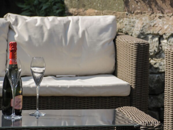 A glass table with a bottle and a wine glass. - Trevor Cottage (Llandudno)