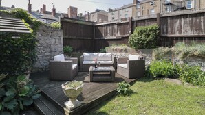 A backyard with outdoor furniture, a stone wall, and a wooden deck. - Trevor Cottage (Llandudno)