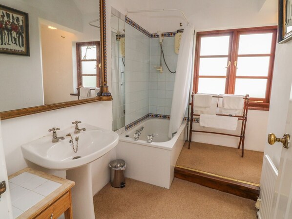 A bathroom with a sink, bathtub, and shower. There is a towel rack and a trash can. - Tom's House (Ilfracombe)