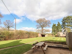 A well-maintained backyard with a picnic table, a small shed, and a lawn. - 1 Organsdale Cottages (Tarporley)