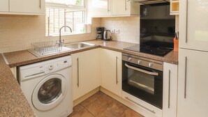 Une cuisine de taille réduite équipée d’un lave-linge, d’une cuisinière et d’un évier.