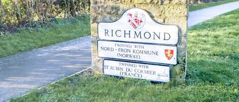 Señal de Richmond con información sobre su ciudad hermana y un cartel indicando estacionamiento gratuito con disco.