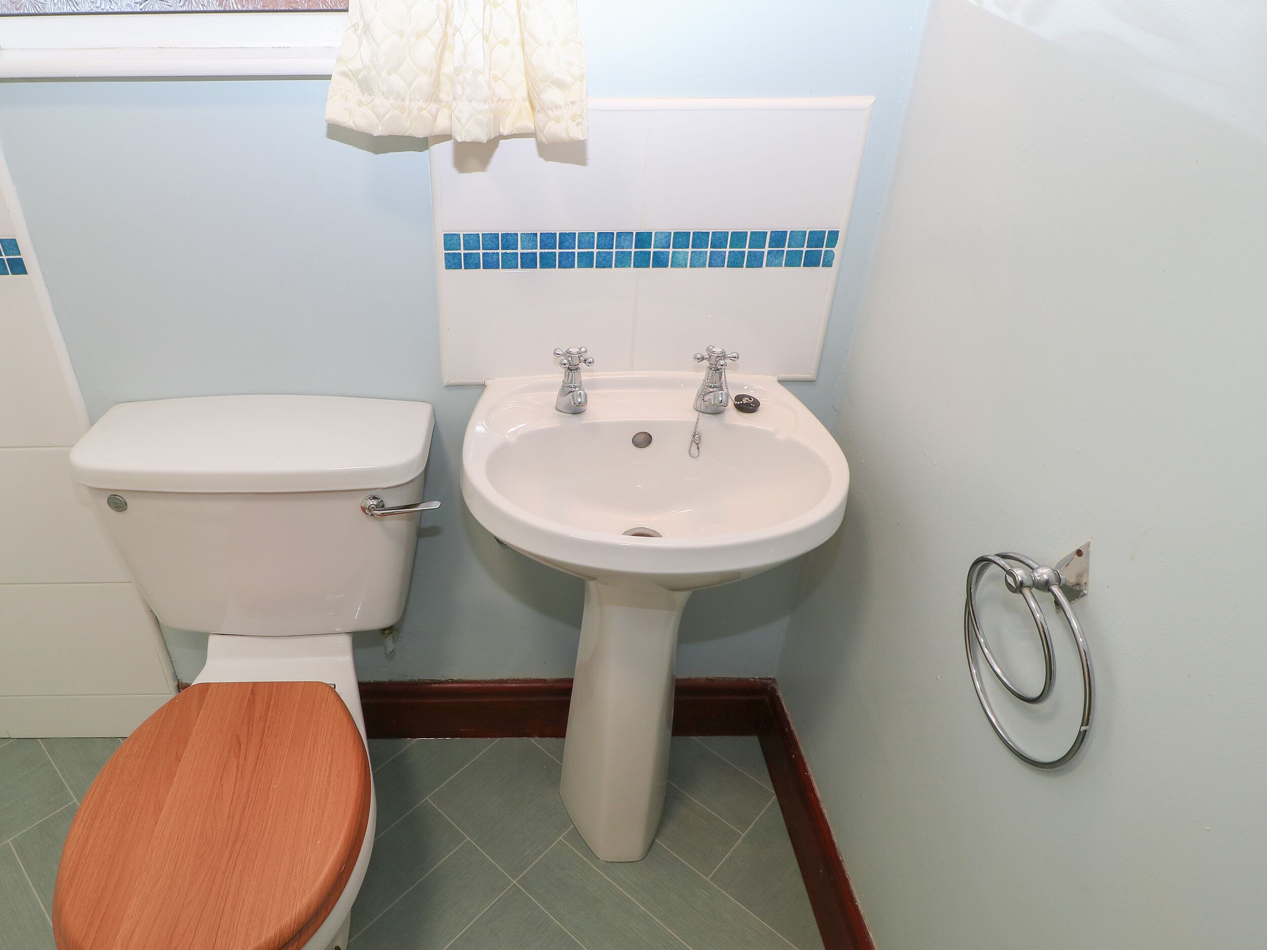 A bathroom with a toilet, sink, and wooden toilet seat.