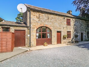 A stone building with a satellite dish, two wooden doors, and a large arched window. - Westfield Cottage (Barnard Castle)