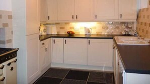 Een keuken met witte kastjes, een zwart aanrecht en een betegelde spatwand.