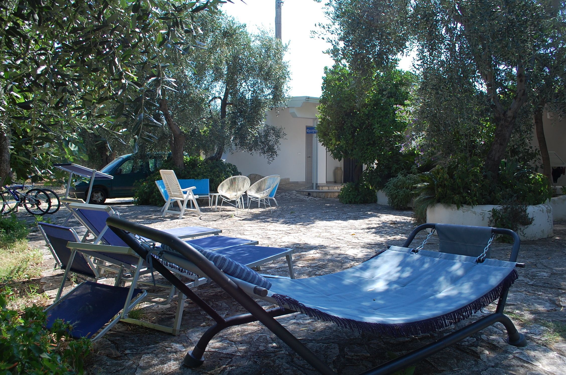 A patio area with lounge chairs, a table, and a car parked nearby.