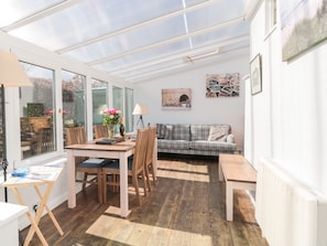 Relax in this spacious room with a dining table, sofa, and side table, perfect for unwinding.