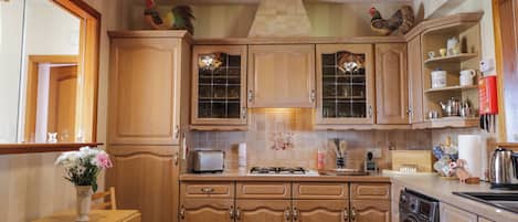 A kitchen with wooden cabinets, a dining table with chairs, a washing machine, and hanging light fixtures.