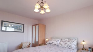 A bedroom with a bed, nightstands, a wardrobe, and a chandelier. - Braehead Croft (Buckie)