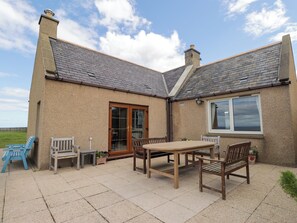 A house with a tiled patio, a wooden table, and several chairs.