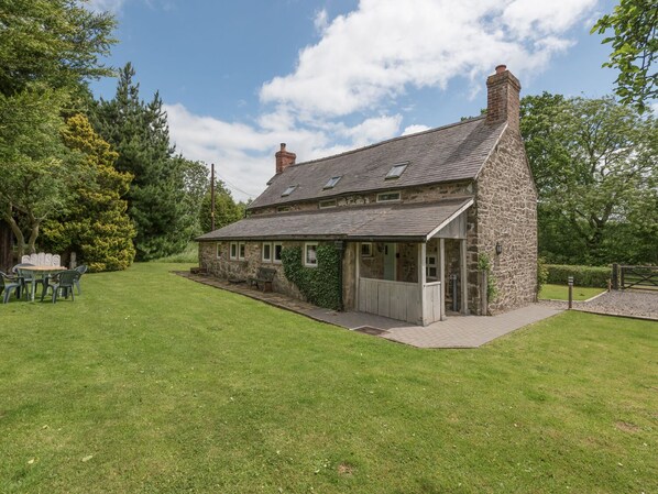 A stone cottage with a sloped roof, a small porch, and a grassy yard. - Hillgate House (Shrewsbury)