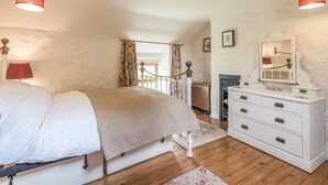 Een slaapkamer met een bed, een dressoir, een spiegel en een open haard.