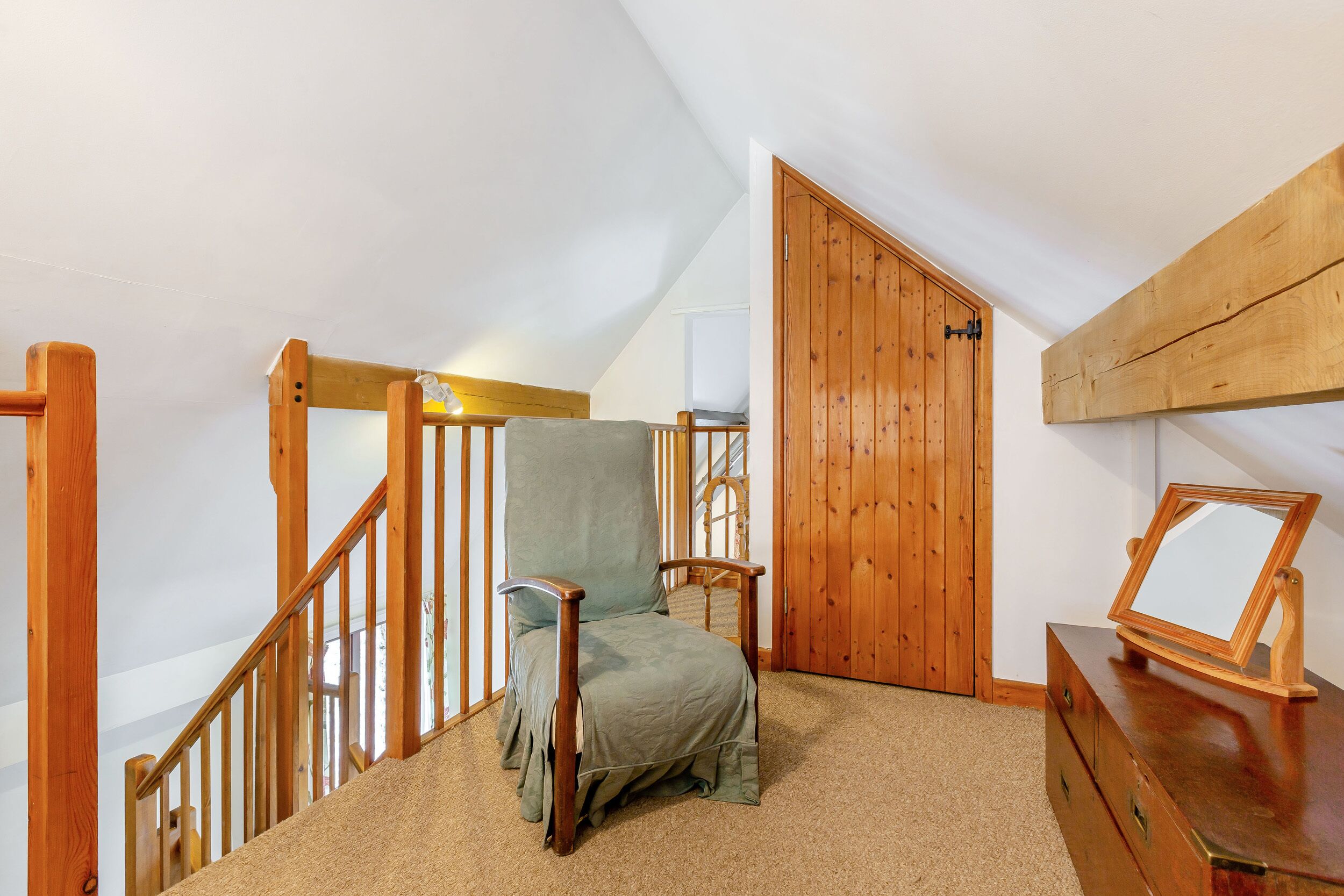 A room with a wooden chair, a wooden dresser, and a wooden door.