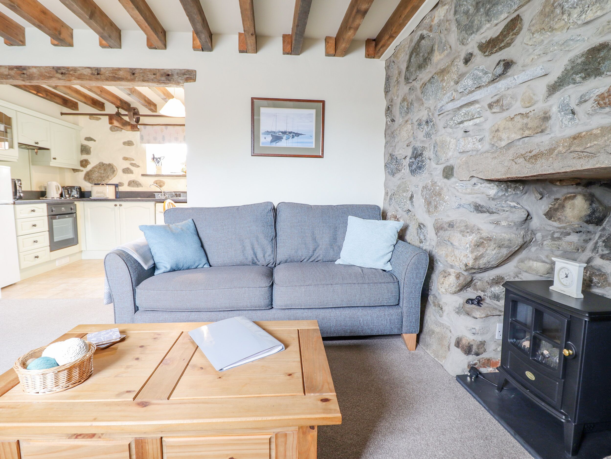 A cozy living room with a grey sofa, a wooden coffee table, and a stone wall.
