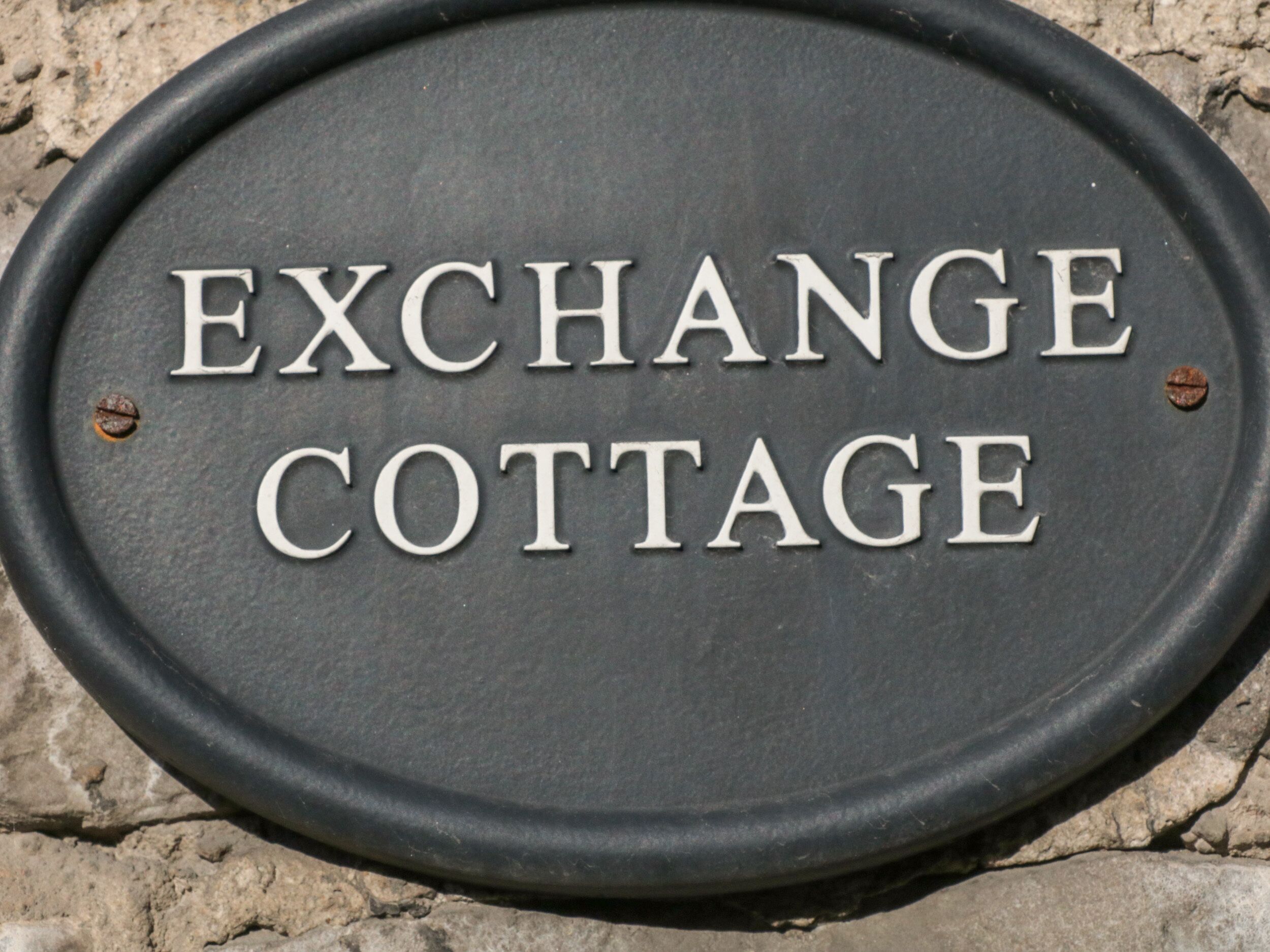 A metal plaque with the words "EXCHANGE COTTAGE" engraved on it.