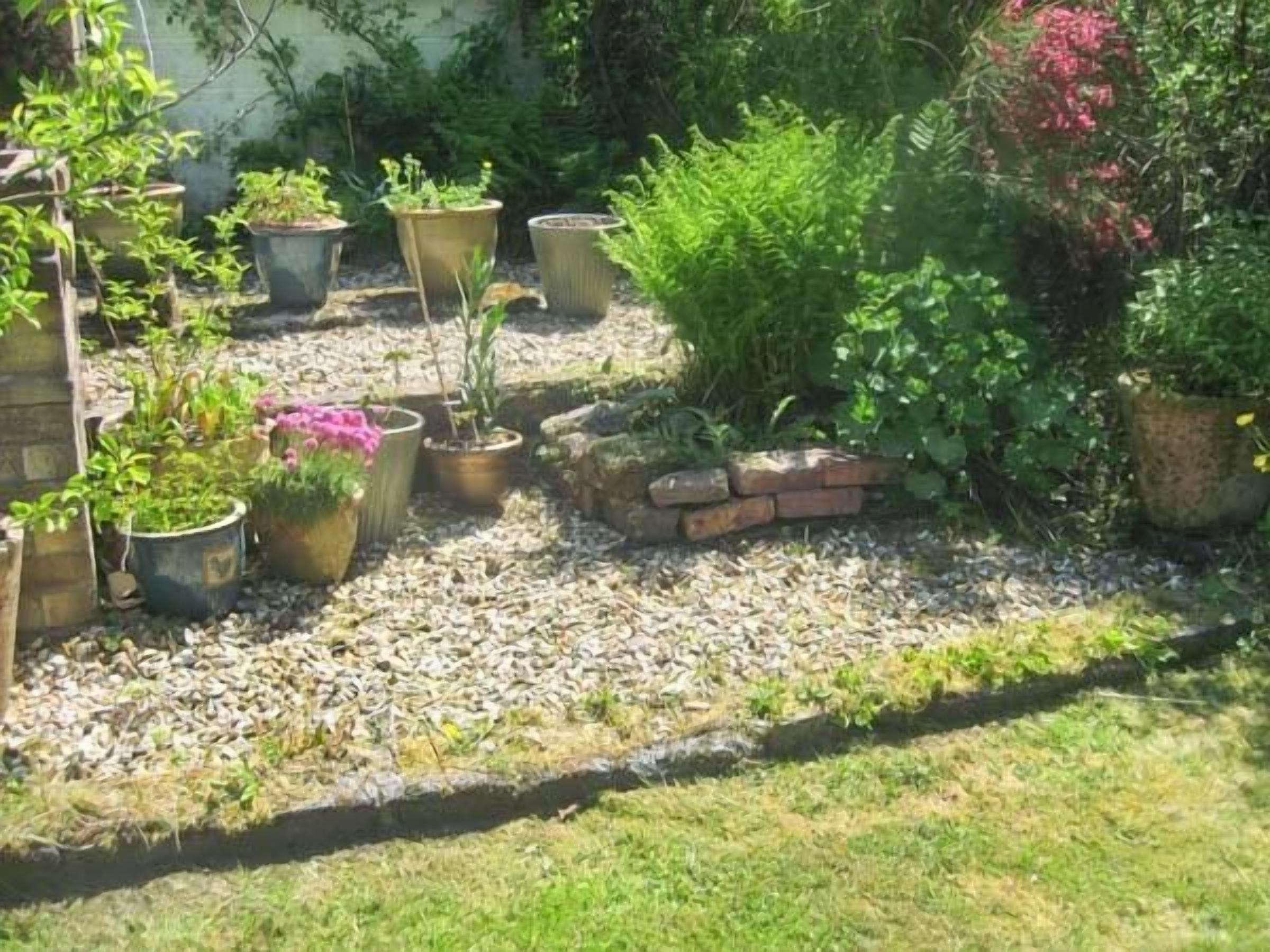 A garden with various potted plants and a brick wall.