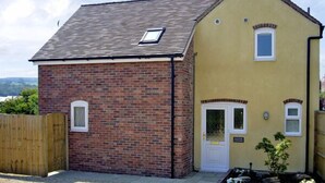 Une maison à deux étages avec une extension en briques et une façade jaune.