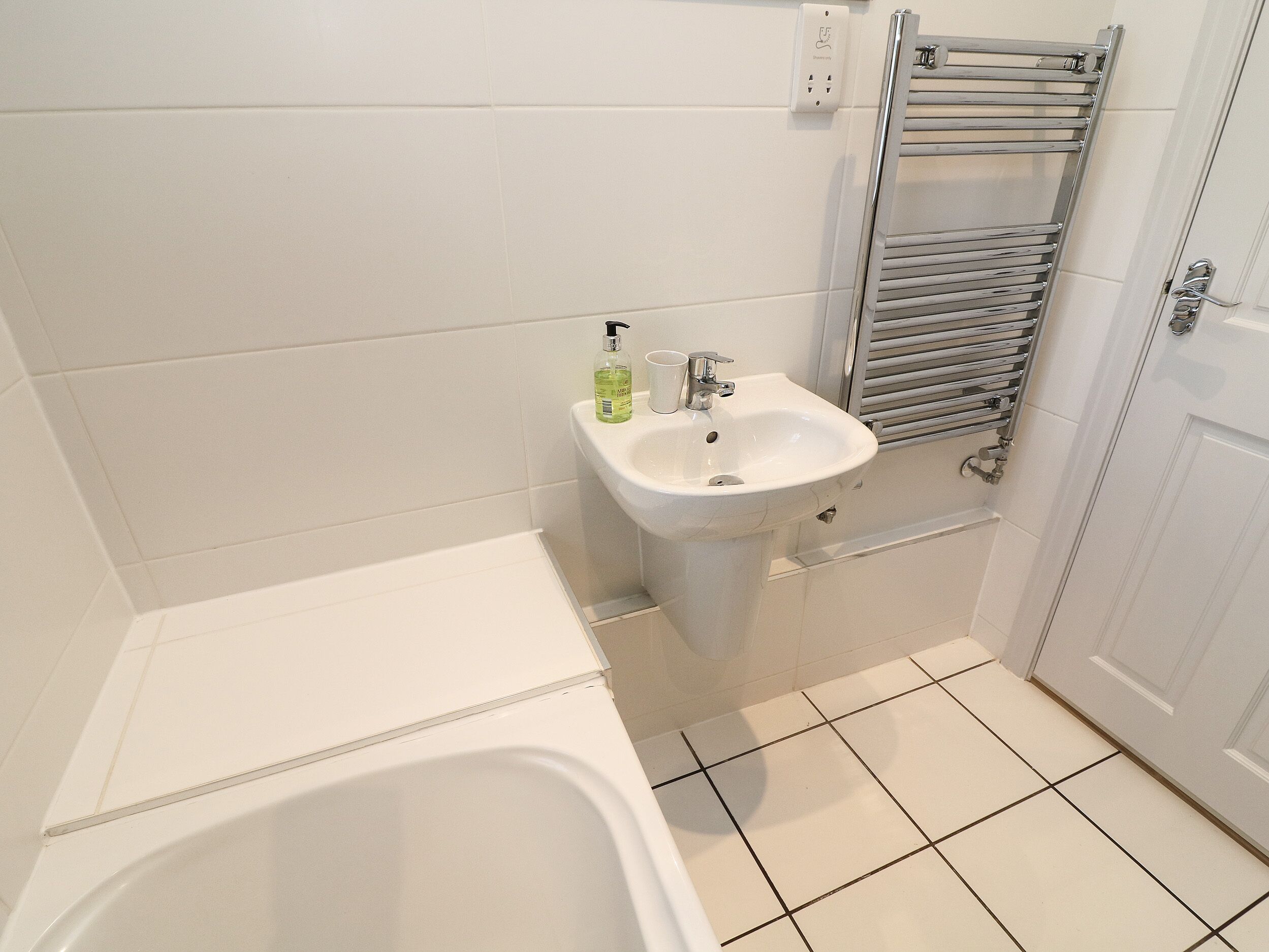 Un baño con bañera, lavamanos y un perchero para toallas.