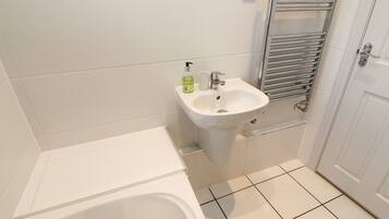 Un baño con bañera, lavamanos y un perchero para toallas.