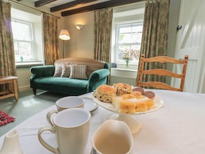 A cozy room with a green sofa, a dining table with a plate of food, and a chair. - Bill's Place (Leyburn)