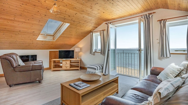 Ett mysigt vardagsrum med ett träpanelat tak, en soffa, ett soffbord och en tv.